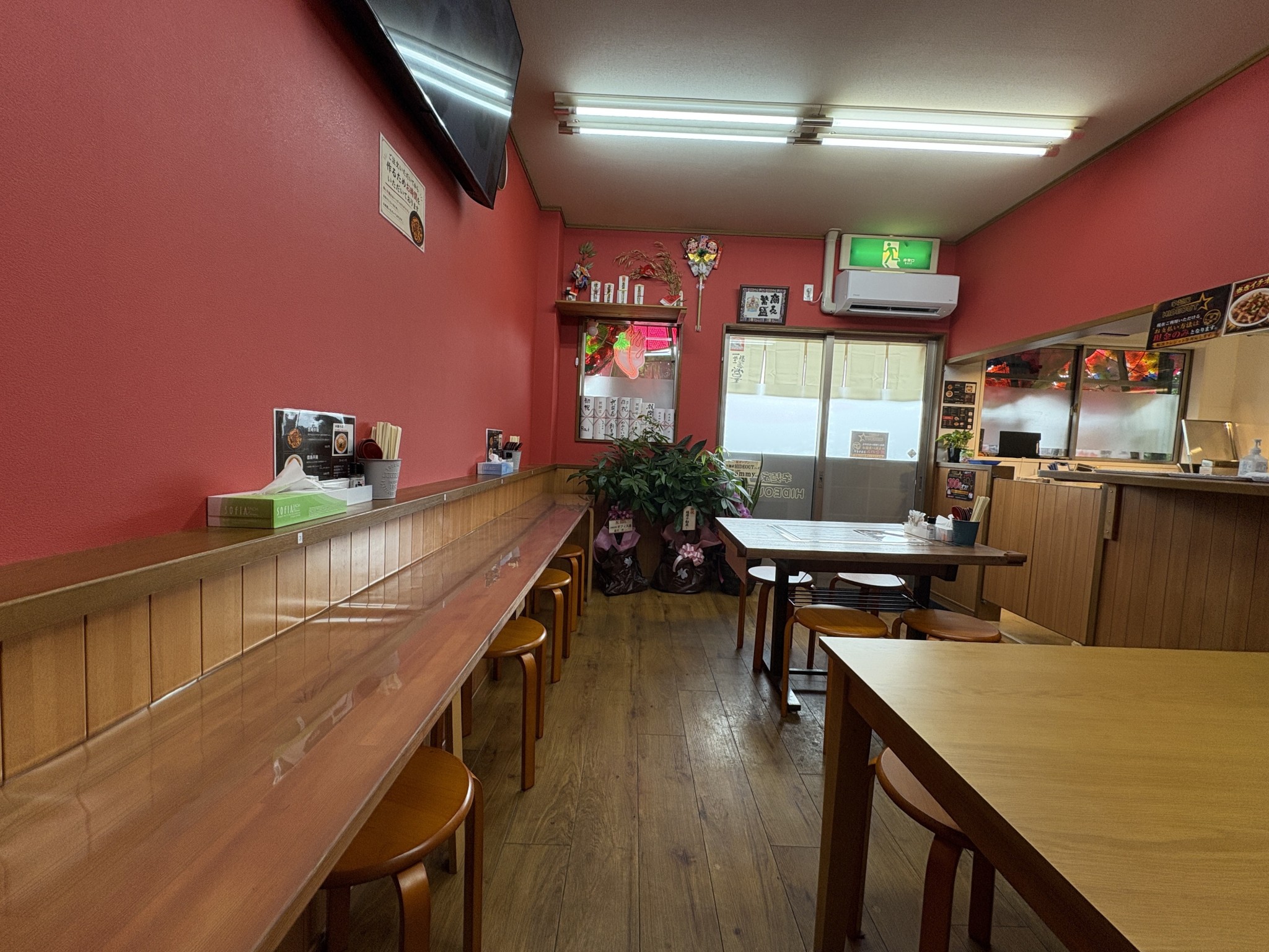 赤い壁と木製カウンターが特徴の辛麺家 HIDEOUT店内