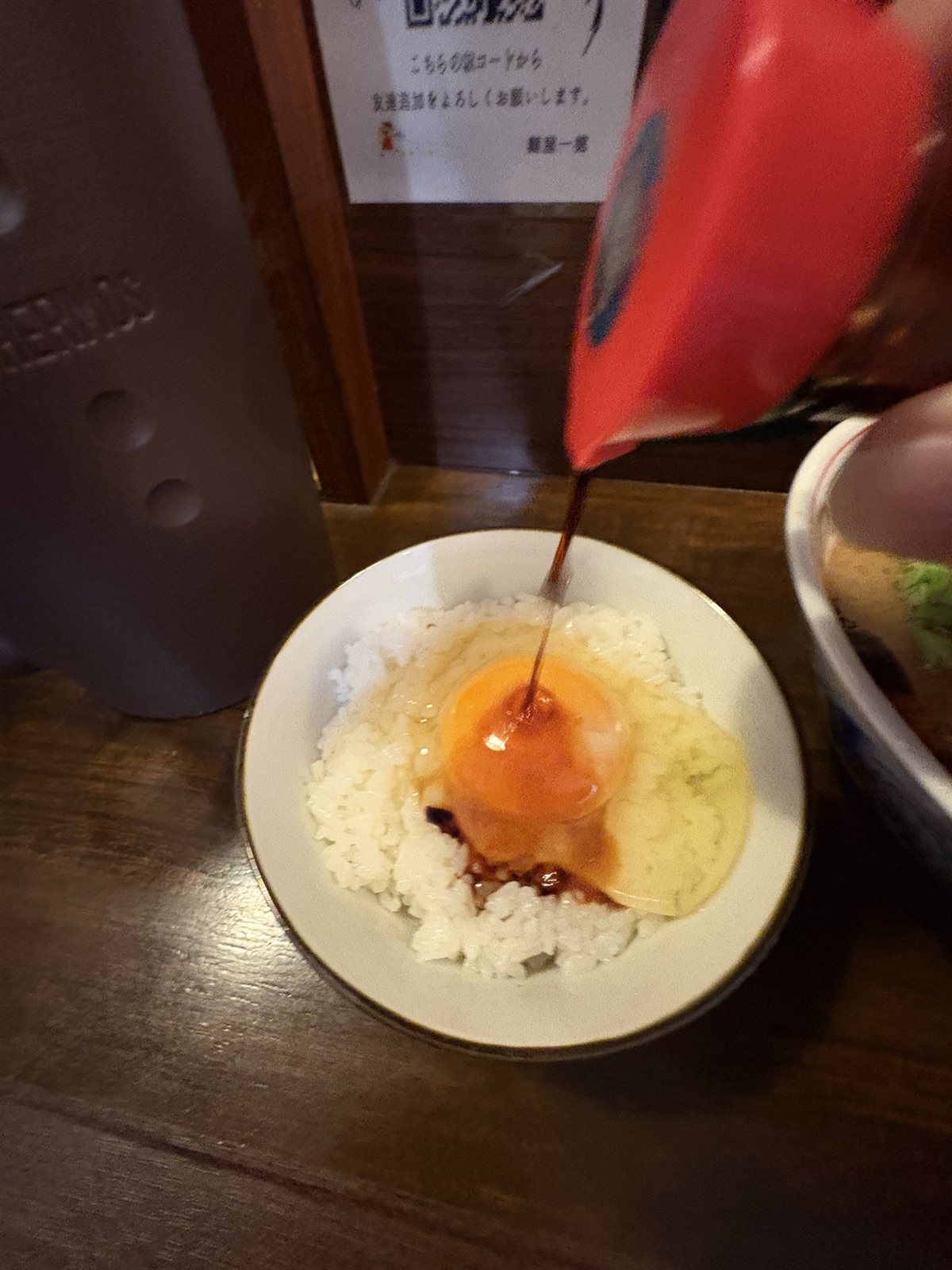 ごはんにのせた生たまごにしょうゆをかけるところ